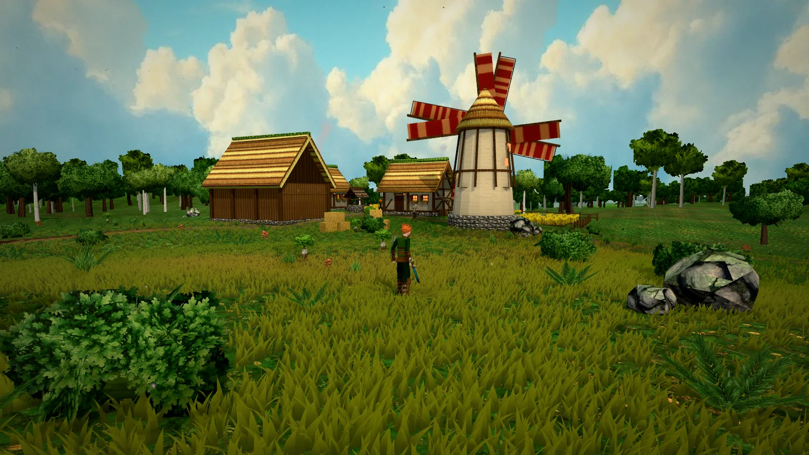 Eine Windmühle mit roten Flügeln und Scheune auf einer Wiese im Eschenhain